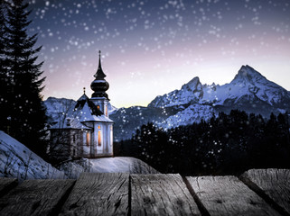 kleine Dorfkirche in verschneiter Berglandschaft am Abend 
