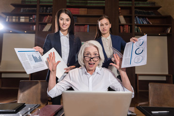 Tired boss and her female colleagues posing in office