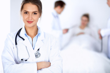 Female doctor smiling on the background with patient in the bed