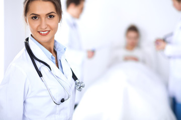 Fototapeta premium Female doctor smiling on the background with patient in the bed