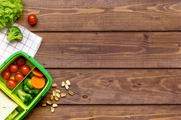 green lunch box for kid on wooden background top view