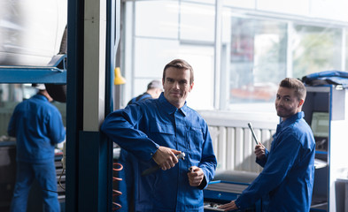 Obraz premium Cheerful auto mechanics holding tools