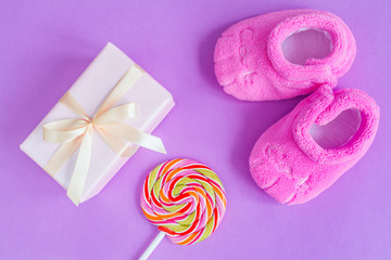 baby's bootees and gift box on purple background
