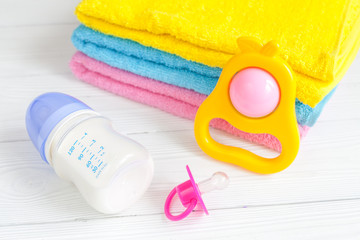 baby bottle with milk and towel on wooden background