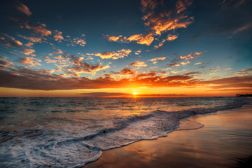 Panele Szklane  Sunrise over the beach. Waves washing the sand.