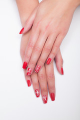Beautiful female hands with professional red manicure with Christmas design  on a white background.