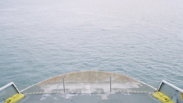 Looking down on the bow (front) of a vehicle transportation ferry as it moves across the sea