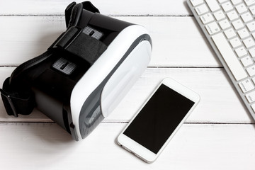 virtual reality glasses with smartphone, keyboard on wooden background