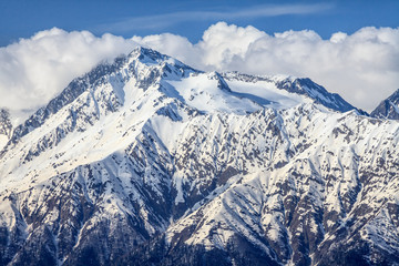 Beautiful mountain scenery of the Main Caucasian ridge with snowy peak on blue cloudy sky background