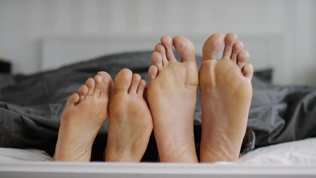 4K Happy feet of a couple doing a silly dance in bed