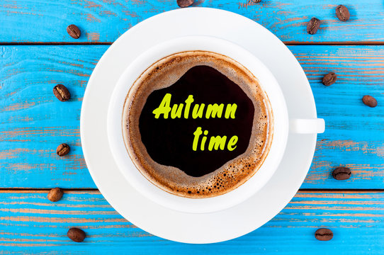 Autumn time inscription on top view morning coffee cup at blue wooden background