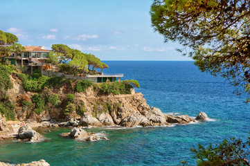 Luxury modern house on the cliff, rock in the edge. Bay and crystal clear water of Mediterranean Sea. Amazing blue green sea and sunny day.