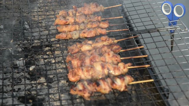 Skewer chicken pieces roasting on the grill and smoke