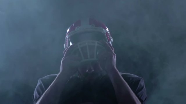Football removes his helmet from his head in the smoke. Slow motion