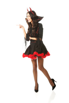 Full length woman wearing devil clothes pointing to the left