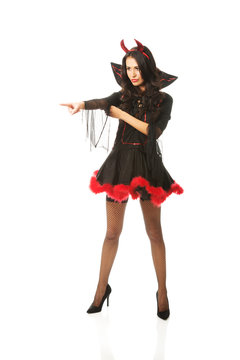 Full length woman wearing devil clothes pointing to the corner