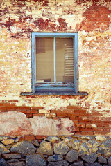 Rustic old blue wooden window frame on historic building. Distressed rendered brick wall.