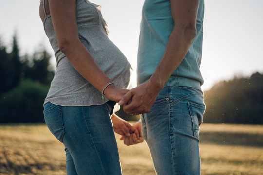 Couple expecting a child holding hands facing each other.