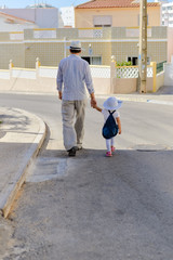 Back view of child with male walking holding hands wearing hat, road outdoors background