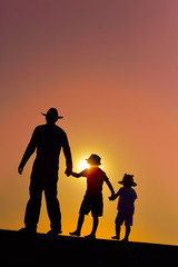 Fototapeta na wymiar Beautiful sunset silhouette of father with kids, outdoors background