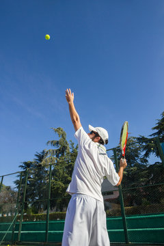 Professional tennis player is doing a kick tennis on a tennis court on a sunny summer morning. He is dressed in sportswear. 
