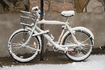 Fototapeta na wymiar Bike covered with fresh snow in Montreal during snow storm (November 2016)