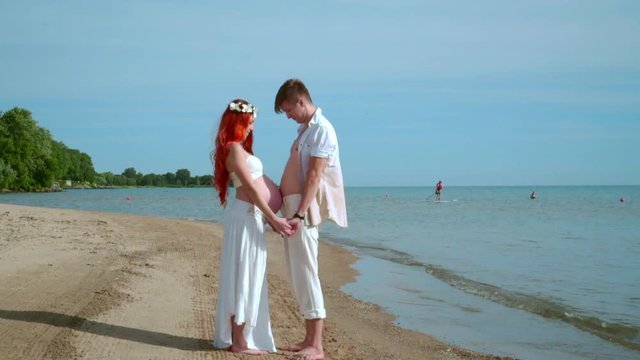 Expecting parents concept. Pregnant couple on sea beach. Man touching pregnant belly. Love couple touching belly. Pregnancy concept. Husband caring about pregnant woman. Love couple on sea beach