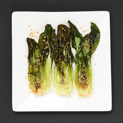 Baked bok choy or pak choi seasoned with soy sauce and roasted sesame seeds, photographed overhead with natural light