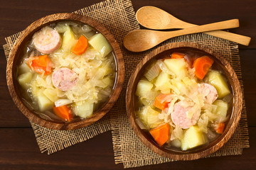 Sauerkraut Eintopf mit Karotten, Kartoffeln und Würstchen, fotografiert mit natürlichem Licht