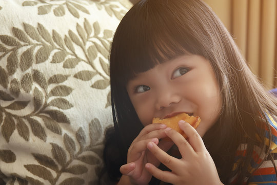 Asian Adorable Child Or Little Girl Enjoy Eating A Custard Cake