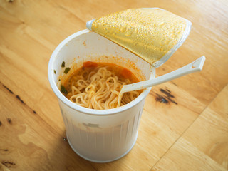 Noodle cup with a Plastic Fork on wooden table