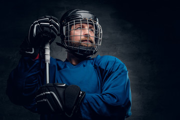 Obraz premium A bearded ice-hockey player in safety helmet holds the gaming st