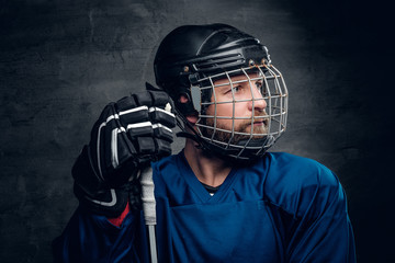 Bearded ice-hockey player in safety helmet holds the gaming stic