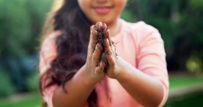 Girl rubbing mud on her hands
