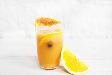 Fresh orange juice in glass on white background. Portion of citrus fresh with orange slice and spices, free space for text. Refreshment, cocktail, vitamins concept