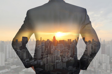 A back turned businessman cityscape and sunset as vision of leader concept.