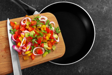 Putting chopped bell pepper with onion in pan, top view