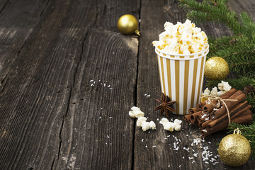 Salty fresh crusty homemade popcorn in silver paper cup in the fashion light background of white brick wall in a New Year's interior with  Christmas balls. selective focus