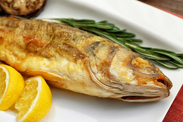 Tasty fish with lemon on kitchen table