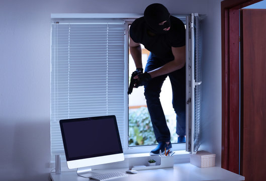 Thief with gun entering office through window