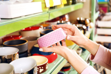 Hands of young woman selecting bowl in pet shop, close up view