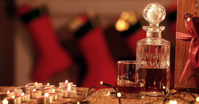 Whisky decanter, tealight candle and christmas lights on plank