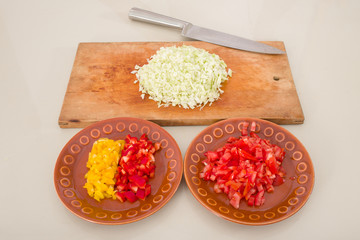 red, yellow pepper and cabbage sliced on board with knife
