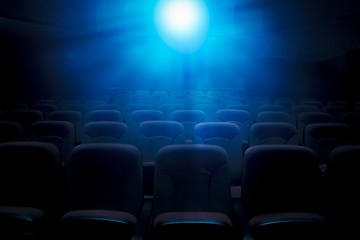 Dark film theater with projection light and empty seats - obrazy, fototapety, plakaty