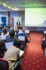 Fototapeta premium Female Host Speaker Speaking in Front of the Audience During Conference