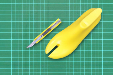 Yellow plastic last shoe and yellow box cutter on rubber secondary cut (cutting mat ), The equipment used for shoe design. (with clipping path)