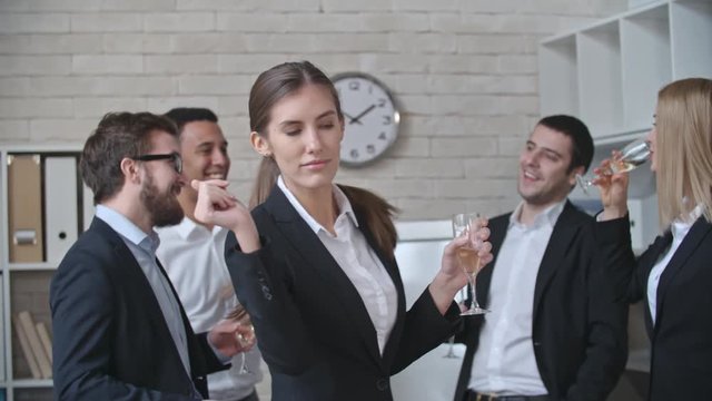 Slow motion shot of office workers dancing with champagne flutes