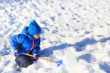 little boy dig and play in snow