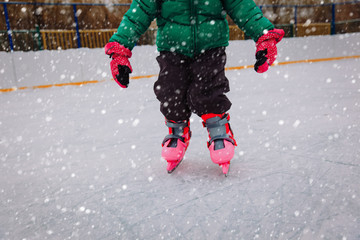 litte girl learning to skate on ice in winter