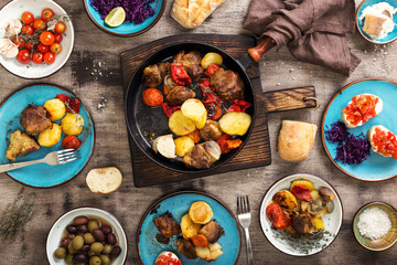 Fried meat with vegetables in a pan, salad and snacks